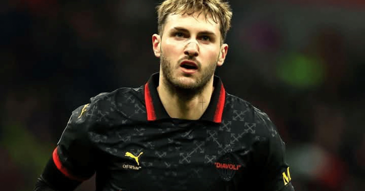 Jugador de fútbol con expresión intensa en partido, camiseta negra con detalles rojos y logotipo de Puma, fondo de estadio desenfocado.