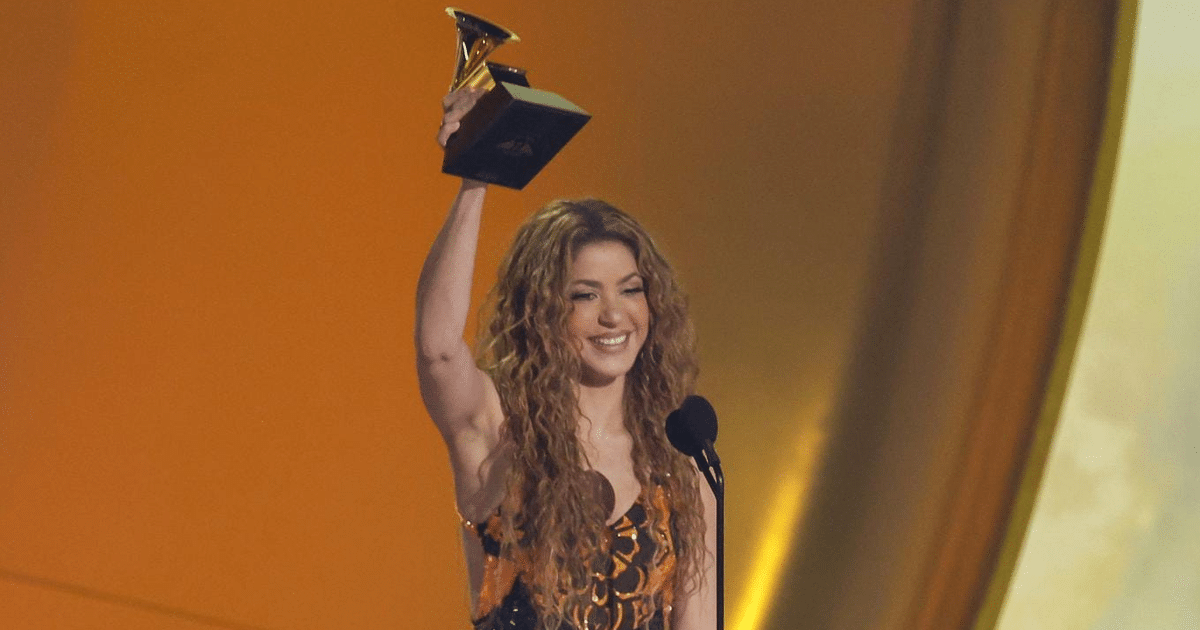 Shakira sonriente con trofeo en alto en evento de premiación Grammy