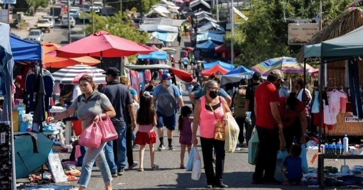 Personas comprando en un mercado al aire libre con sombrillas de colores en Culiacán