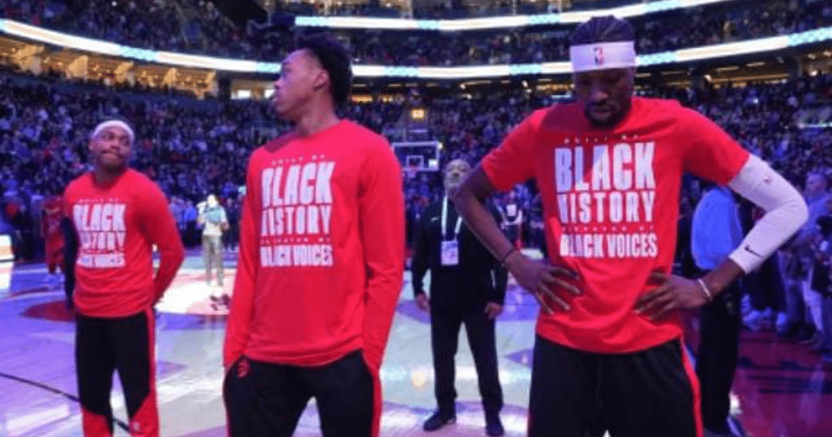 Jugadores de baloncesto con camisetas rojas 'BLACK HISTORY BLACK VOICES' en evento deportivo