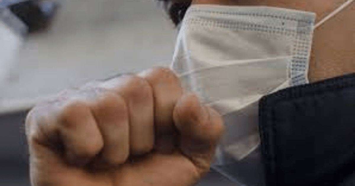 Mano en puño sosteniendo mascarilla blanca, simbolizando medidas preventivas contra la tos ferina en México.