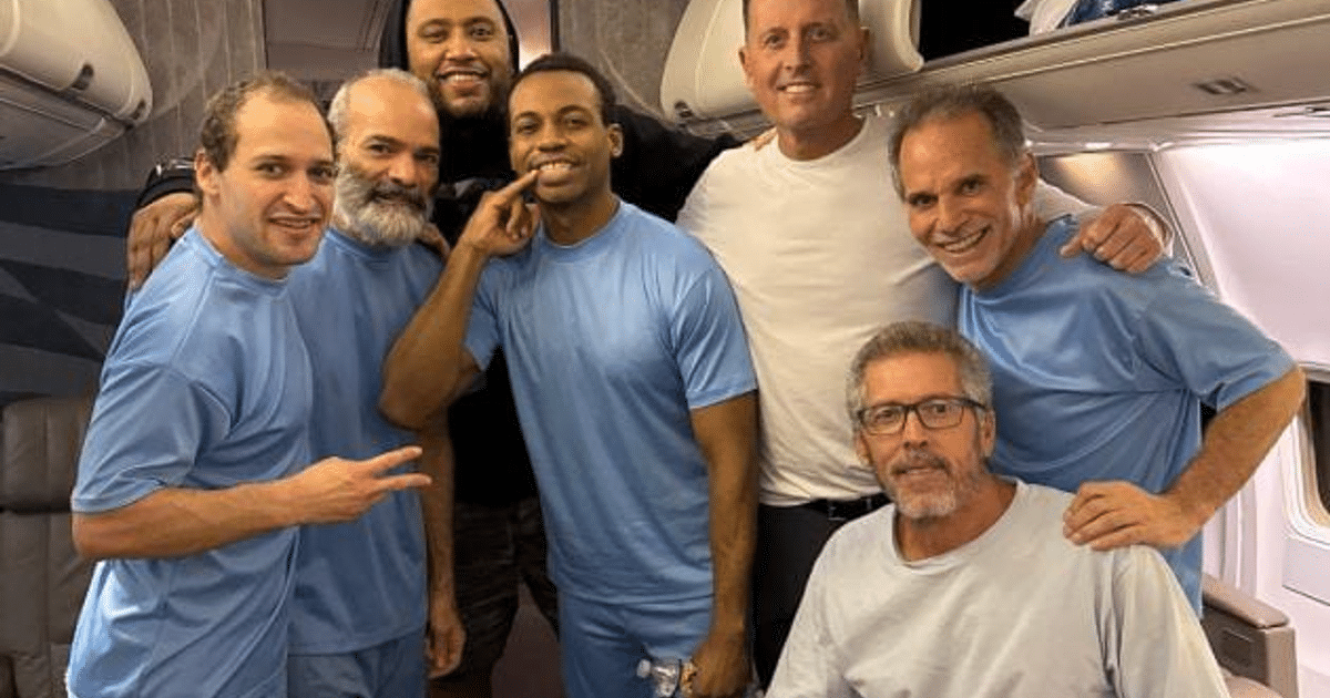 Seis ciudadanos estadounidenses liberados en Venezuela posan dentro de un avión, vestidos de azul y sonriendo.