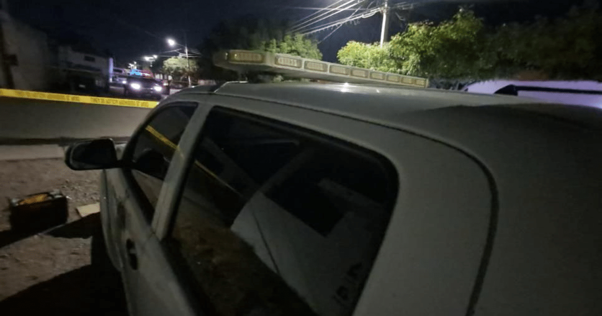 Coche patrulla blanco con luces en el techo y cinta de seguridad amarilla en un incidente nocturno en Villa Juárez, Navolato.