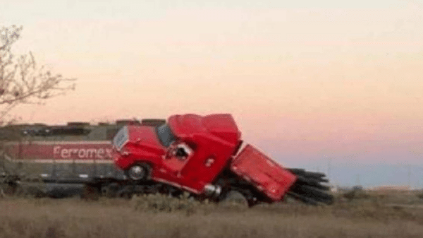 Camión rojo accidentado sobre vagón de tren en Ahome al atardecer