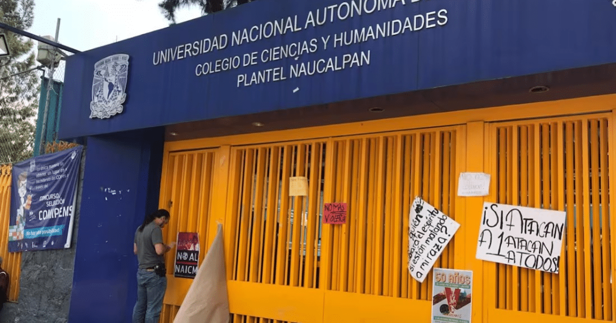 Entrada del CCH Naucalpan de la UNAM con rejas amarillas y carteles informativos
