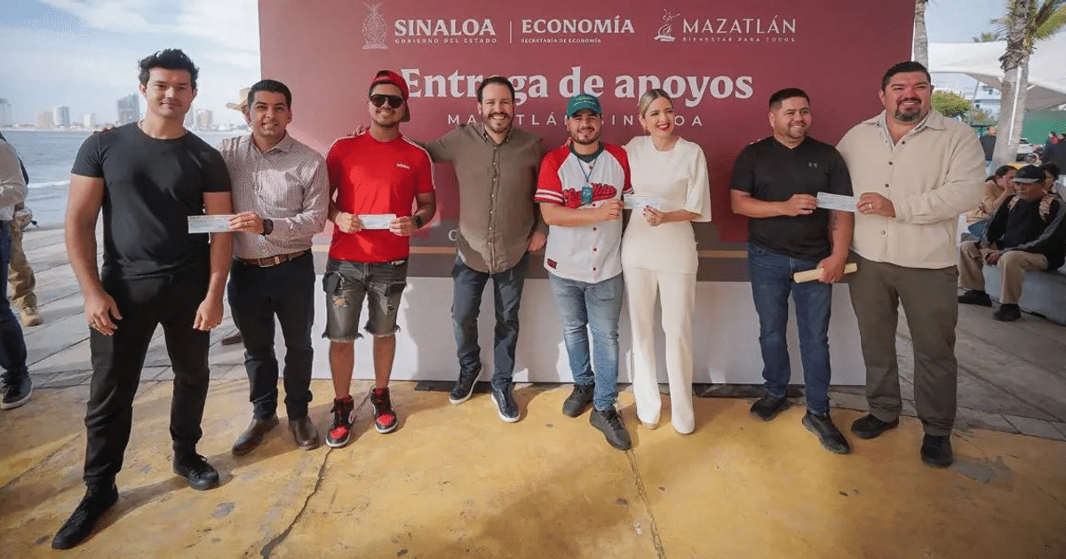 Grupo de personas en evento de entrega de apoyos en Mazatlán, con mar y edificios de fondo.