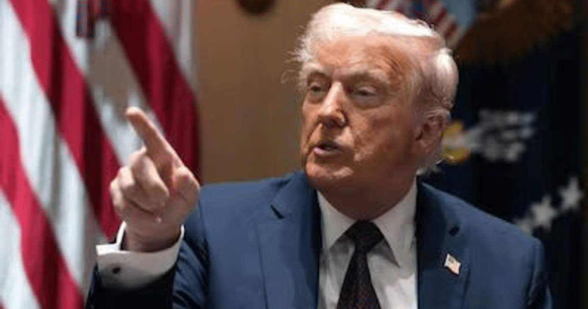 Persona gesticulando mientras habla sobre aranceles recíprocos, con banderas de fondo.