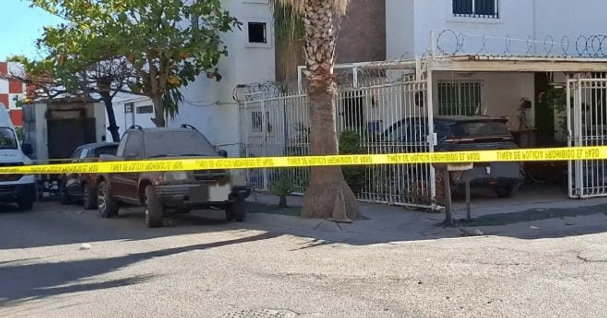 Área acordonada con cinta amarilla en Culiacán, vehículos y casa con reja visible.