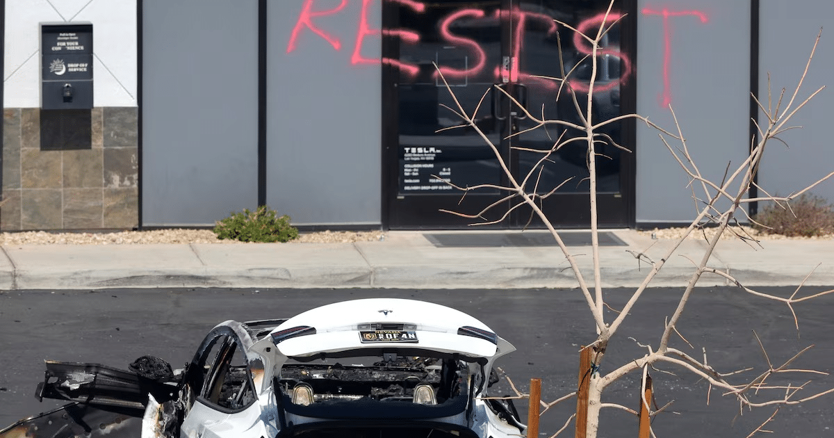 Coche blanco dañado frente a edificio con graffiti 'RESIST' en un entorno urbano descuidado.