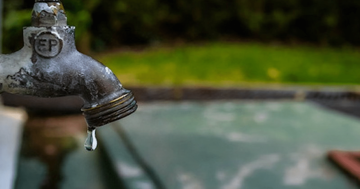 Grifo de metal goteando con fondo verde desenfocado, relacionado con la crisis de agua en Los Mochis.