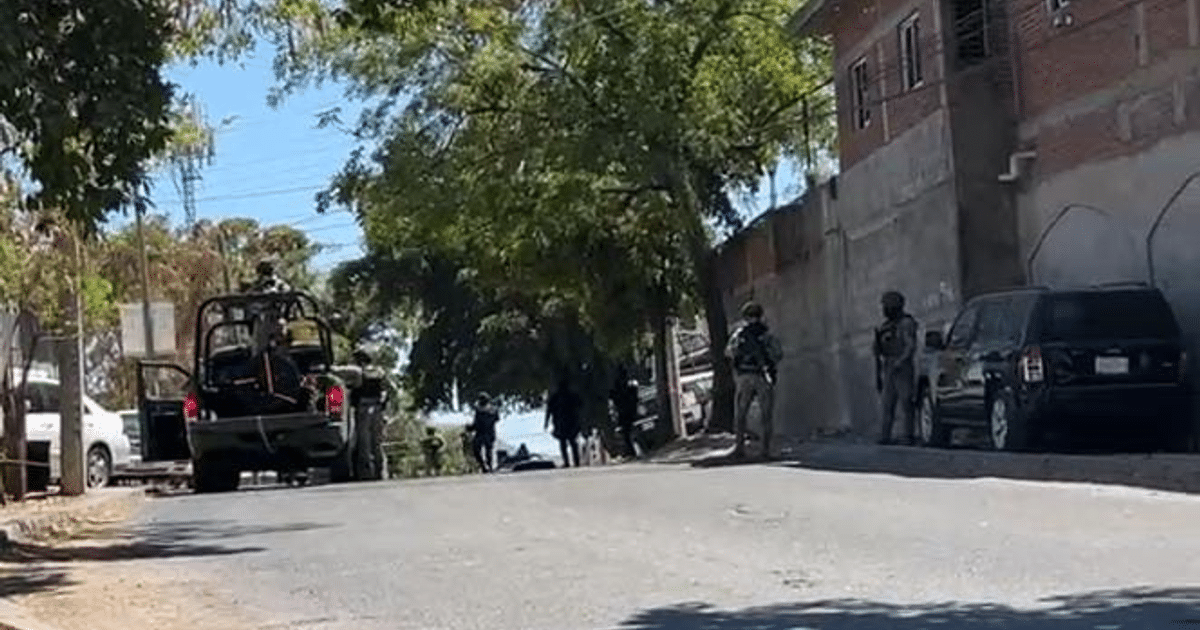Calle en Culiacán con árboles, vehículos y personal de seguridad en operativo.