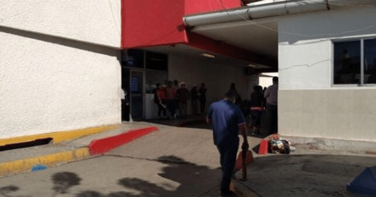 Personas en fila y caminando en un centro de servicio en Culiacán, Sinaloa, con paredes blancas y detalles en rojo.
