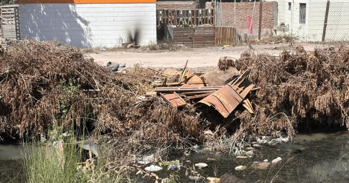 Área urbana con escombros y agua contaminada, reflejando problemas de gestión de residuos en el canal 23+700.