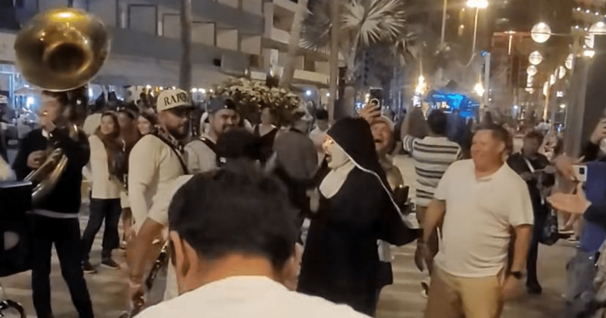 Grupo de personas disfrutando del Carnaval de Mazatlán con un músico tocando la tuba y una persona vestida de monja.