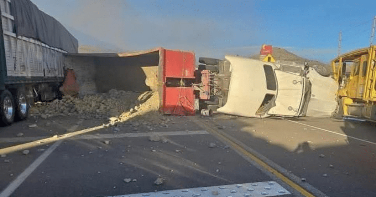 Camión volcado en la autopista Durango-Mazatlán con carga esparcida y vehículo volcado cerca, bajo un cielo despejado y montañas al fondo.