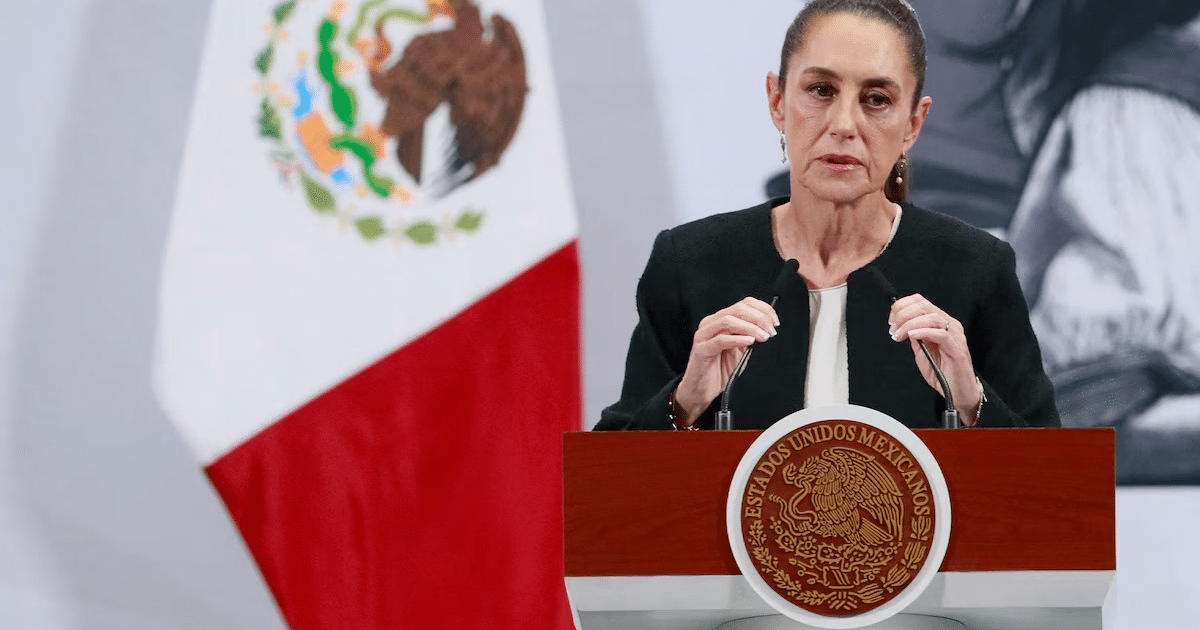 Claudia Sheinbaum en conferencia de prensa con bandera de México