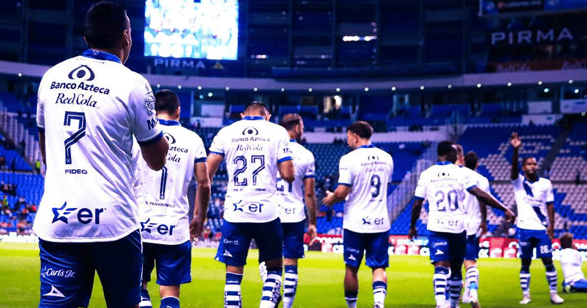 Jugadores del Club Puebla celebrando en el estadio con camisetas blancas y detalles azules.