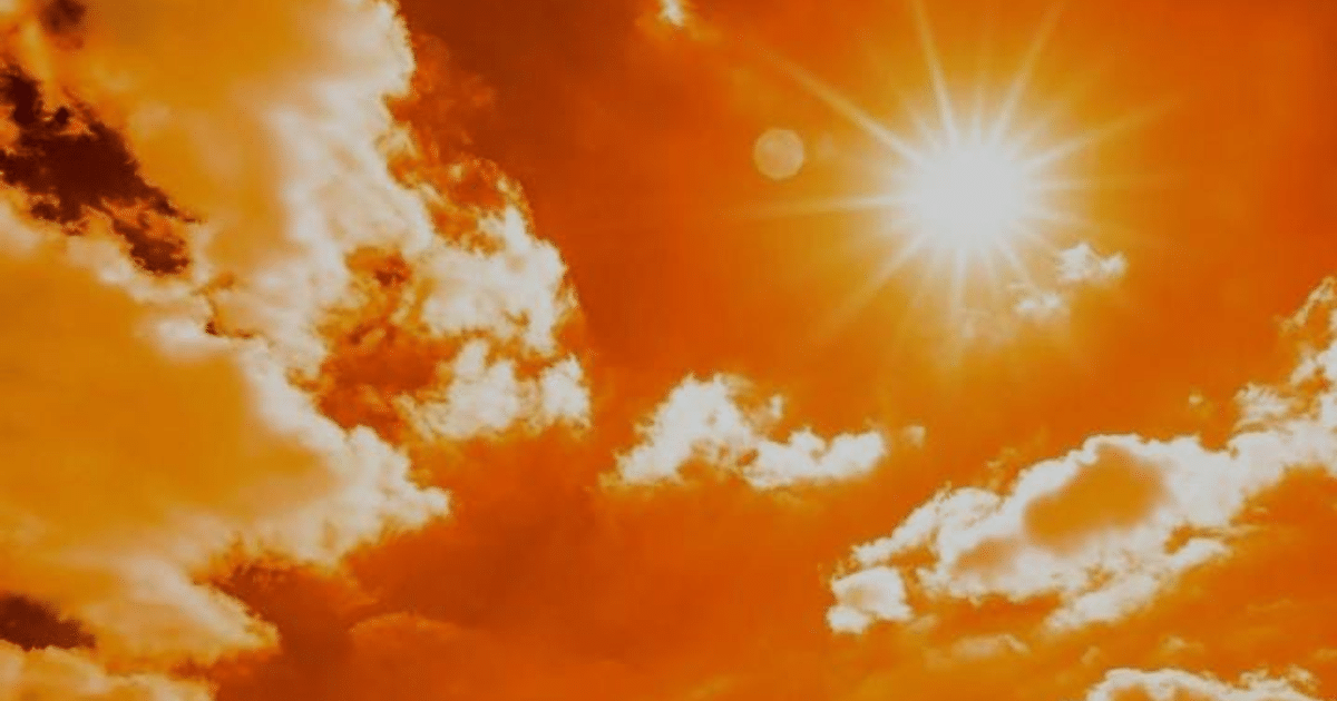 Cielo anaranjado con nubes y sol brillante al atardecer, relacionado con la exposición solar y el cáncer de piel.
