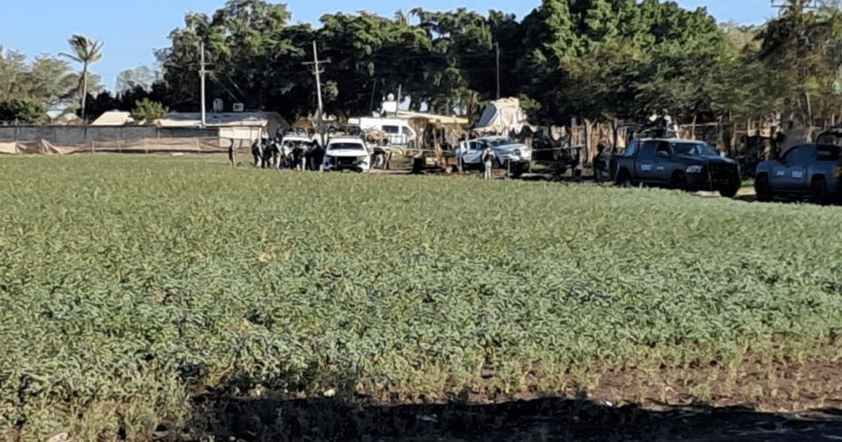 Campo verde en Ejido Canan con personas y vehículos al fondo, escenario de reciente conflicto.