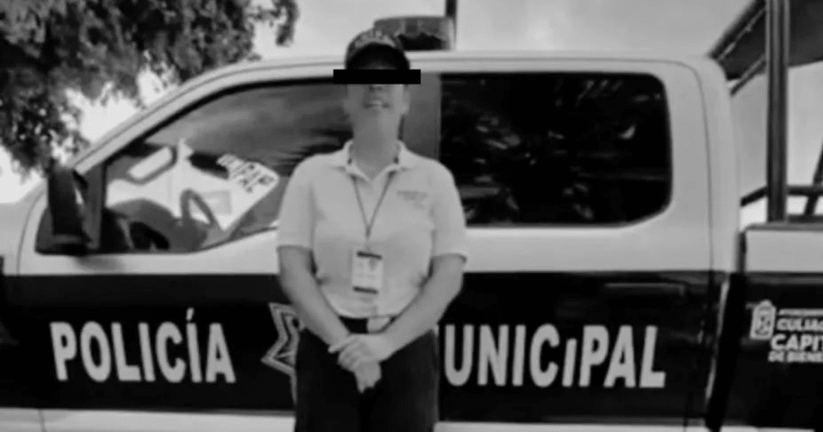 Oficial de policía municipal frente a coche patrulla en escena de crimen al aire libre.