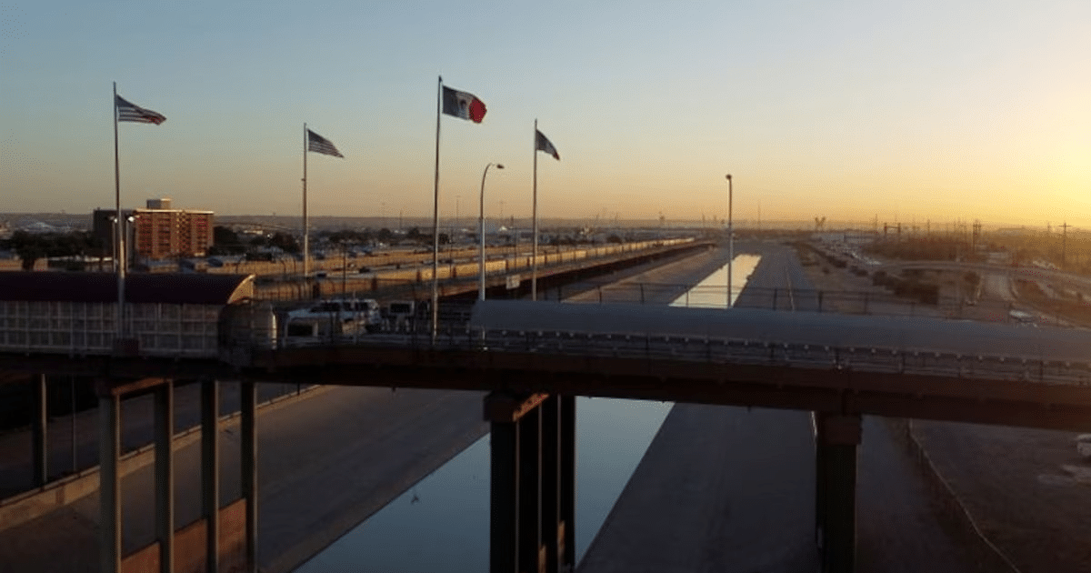 Puente con banderas de México y Estados Unidos al amanecer, simbolizando la conexión fronteriza.
