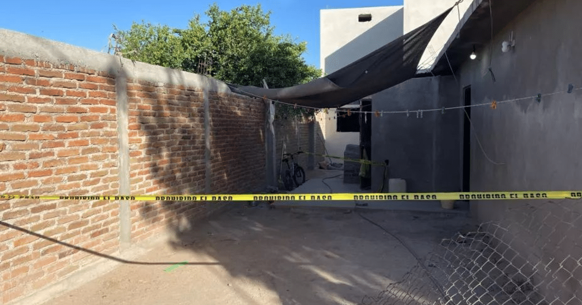 Callejón con pared de ladrillo, bicicleta, tendedero y cinta de advertencia amarilla.
