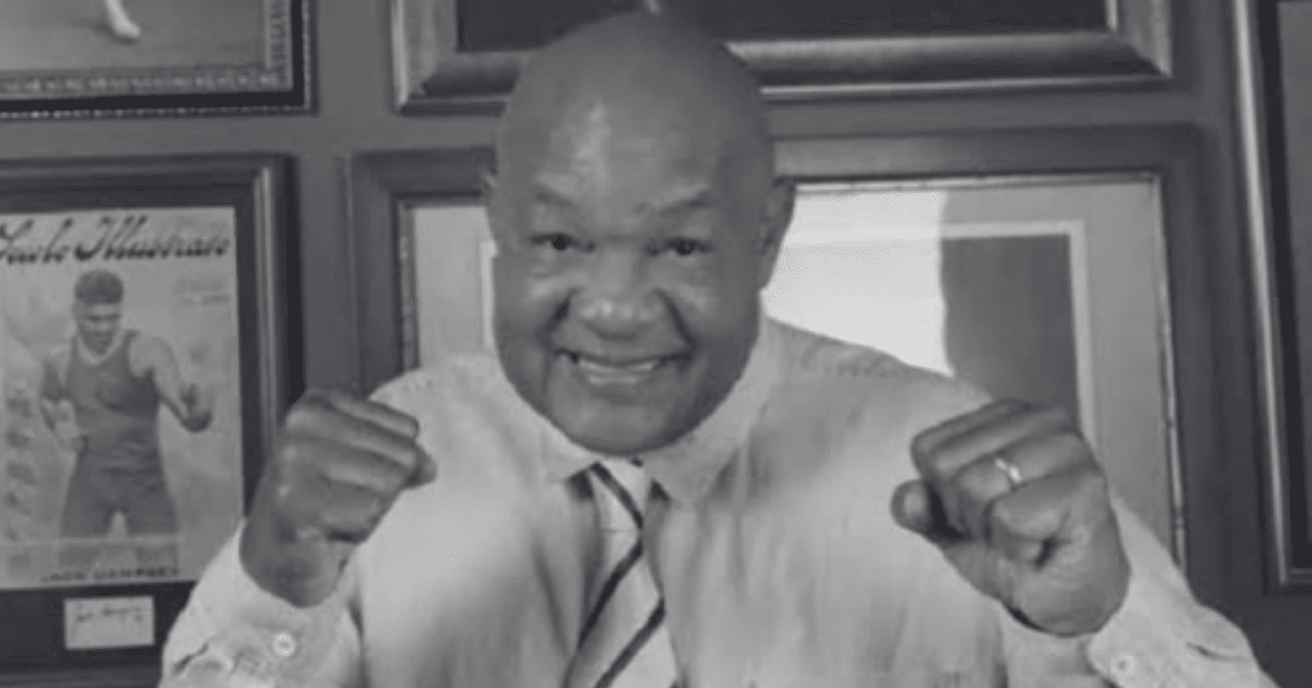Persona sonriendo y haciendo un gesto de lucha frente a cuadros enmarcados, evocando a George Foreman.