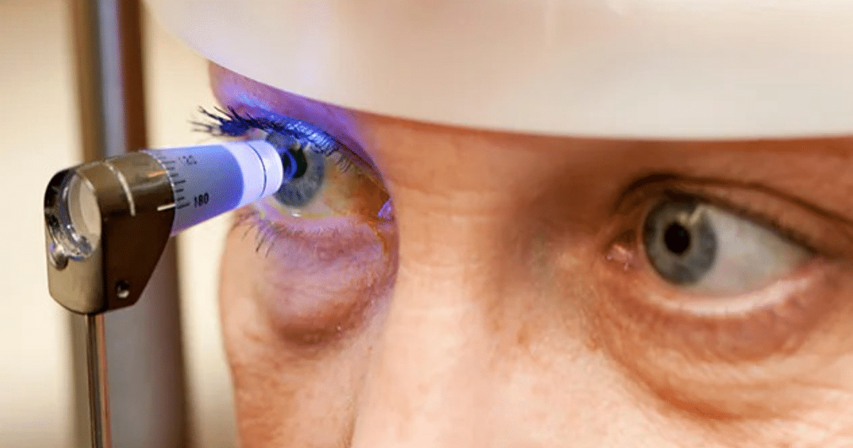 Close-up de un ojo humano iluminado por un dispositivo óptico durante un examen ocular en un ambiente médico.