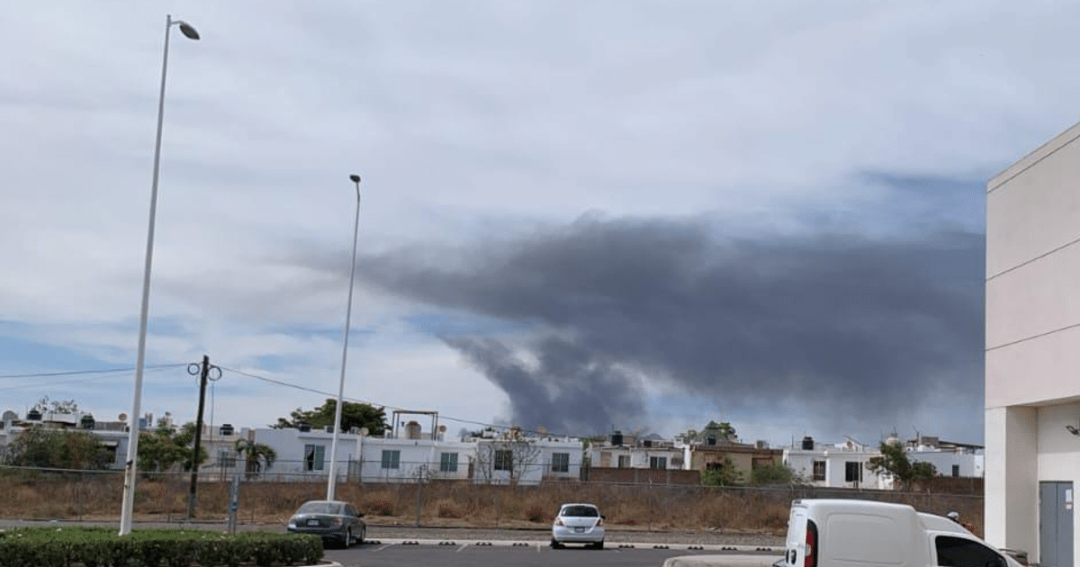 Cielo nublado con humo oscuro sobre Culiacán, vehículos y edificios en primer plano.