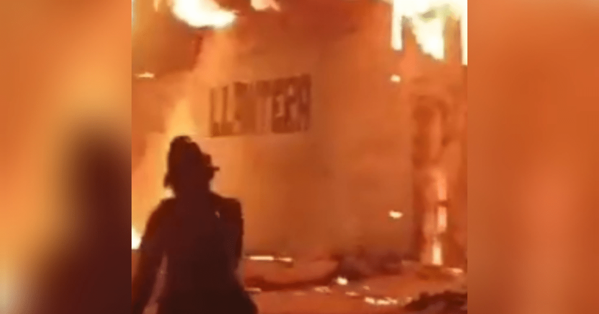 Escena de incendio en llantera de Culiacán con figura humana observando el fuego.