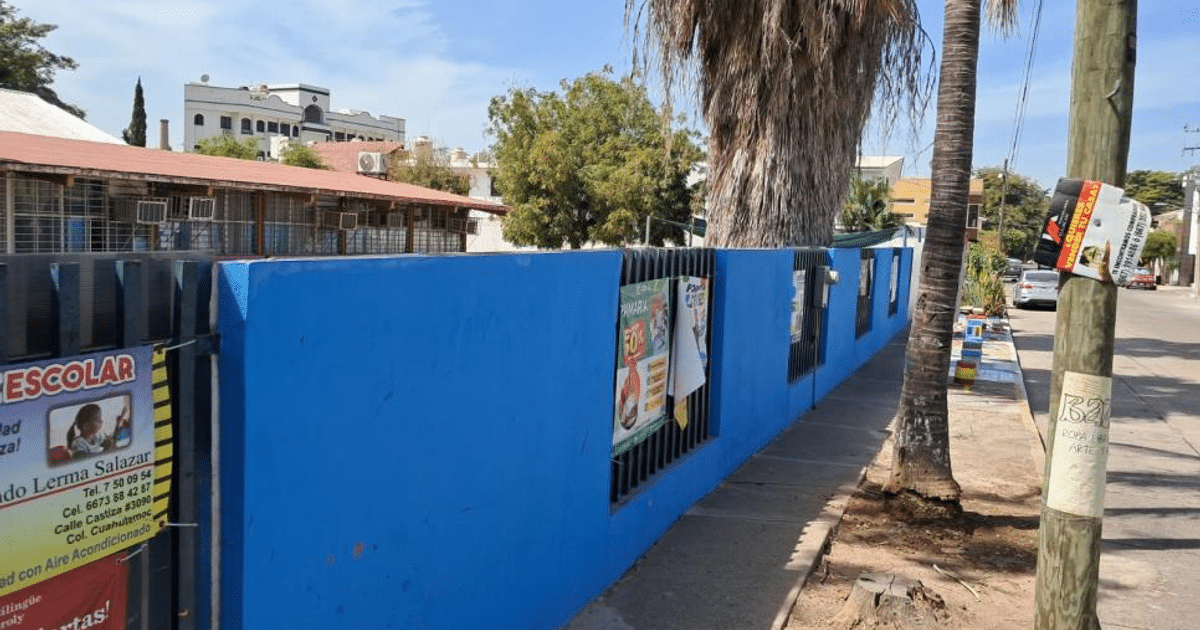 Muro azul con carteles escolares en la colonia Las Quintas, cerca del jardín infantil Luz María Serradell.