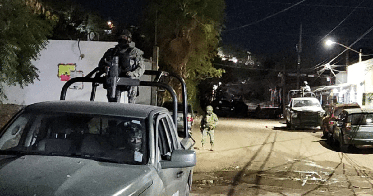 Agentes armados en operativo nocturno en Culiacán, con vehículos y vigilancia en una calle.