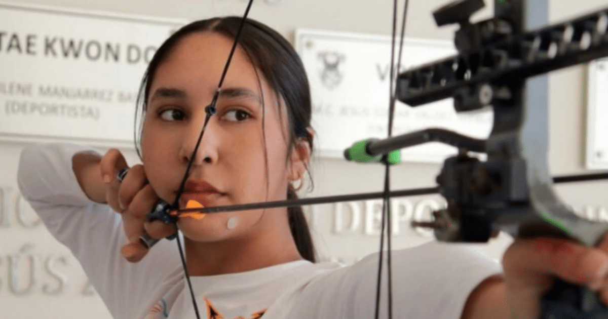 Joven deportista Alison Romero Parra practicando tiro con arco, apuntando hacia un objetivo en un entorno deportivo.