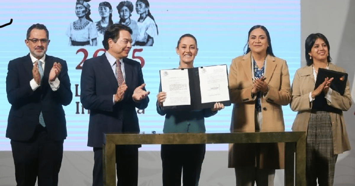 Grupo de personas aplaudiendo mientras una mujer sostiene un documento oficial en un evento sobre maíz transgénico.