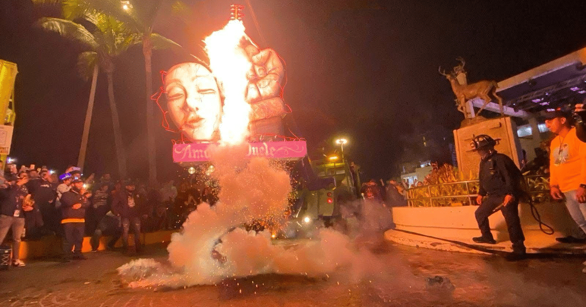 Desfile nocturno en el Carnaval de Mazatlán con estructura iluminada y fuegos artificiales.
