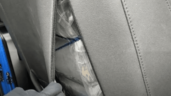 Asiento de vehículo con paquete envuelto en plástico y maleta azul, relacionado con incautación de drogas en Colorado.