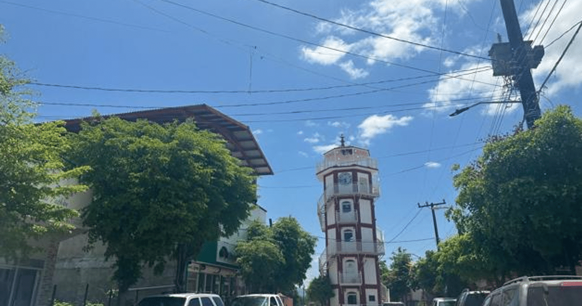 Calle en Choix, Sinaloa con cielo azul, árboles, edificio histórico y vehículos estacionados.