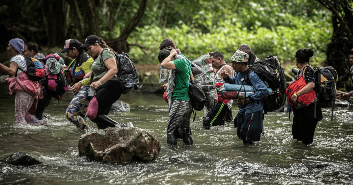 Personas cruzando un río con mochilas en un entorno natural, simbolizando colaboración y esfuerzo conjunto.