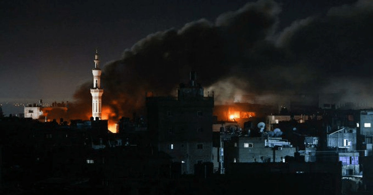 Paisaje urbano nocturno en Gaza con edificios en llamas y humo durante operativos militares.