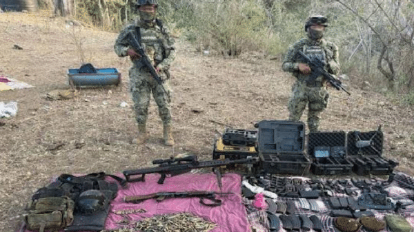 Dos oficiales militares con armas junto a un despliegue de armamento incautado durante el operativo Frontera Norte.