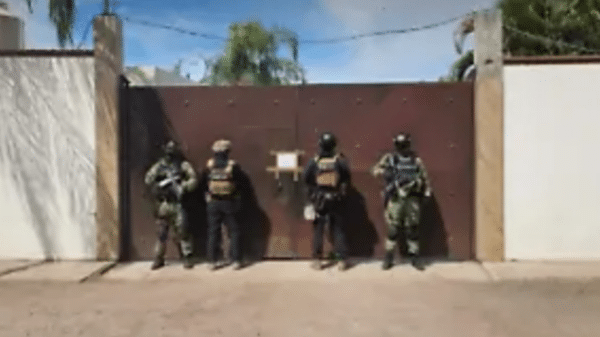 Cuatro agentes tácticos frente a una puerta durante un operativo en Culiacán