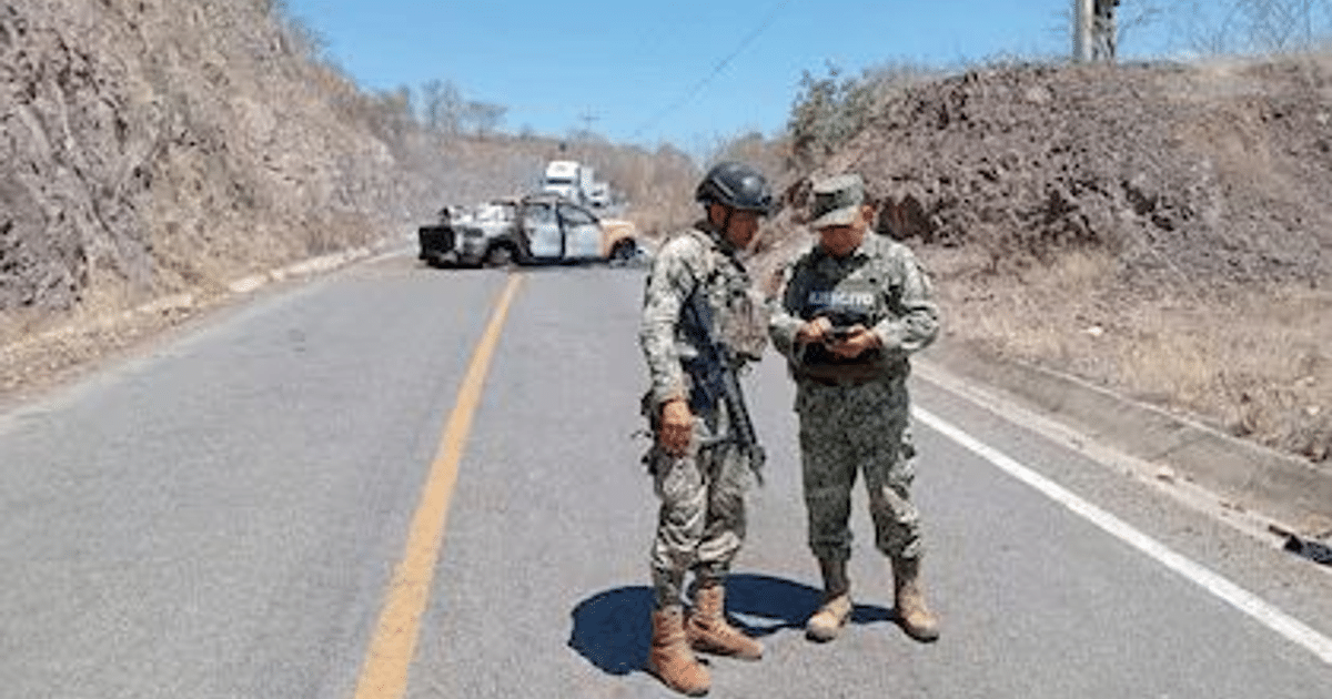 Dos hombres en uniformes militares junto a una camioneta en una carretera montañosa durante un operativo de seguridad en Jalisco.