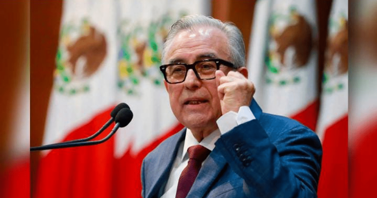 Hombre hablando desde un podio con banderas de México detrás, relacionado con operativos de seguridad en Sinaloa.