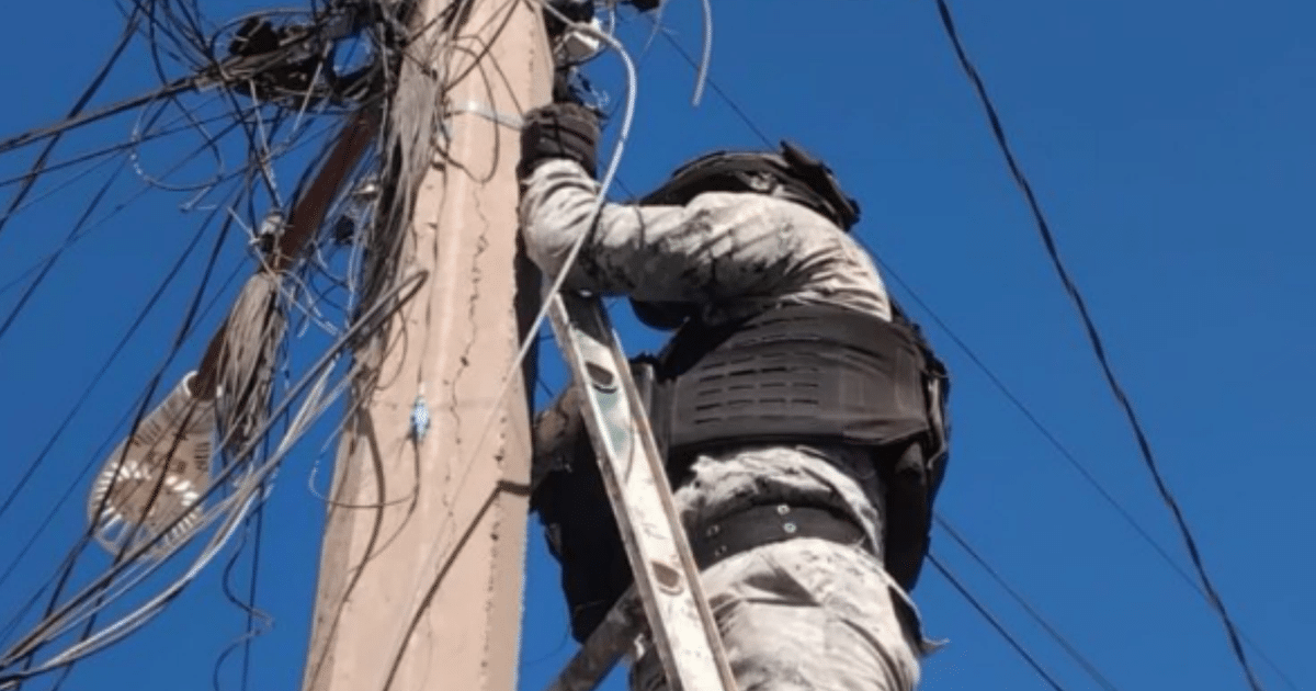 Técnico escalando un poste de luz en Culiacán durante operativo de incautación de cámaras de videovigilancia.