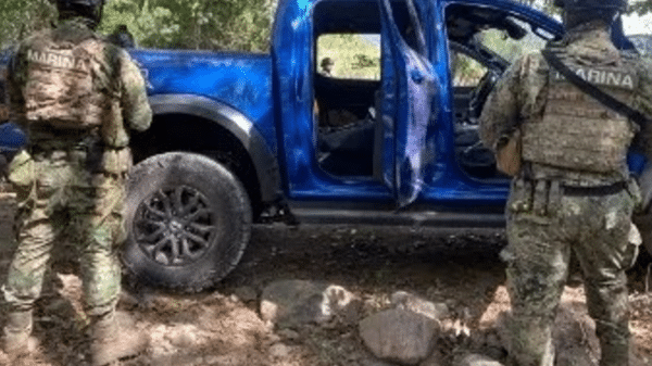 Dos oficiales de la Marina junto a una camioneta azul en un área rural durante un operativo de seguridad en Elota, Sinaloa.