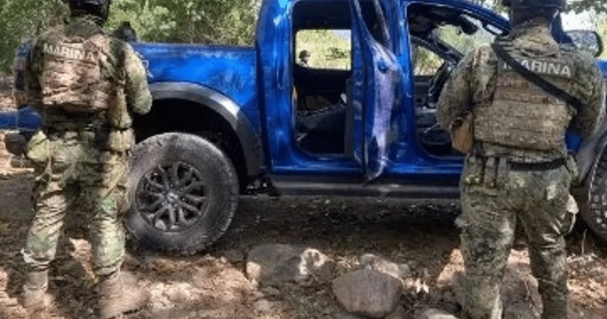 Dos oficiales de la Marina junto a una camioneta azul en un área rural durante un operativo de seguridad en Elota, Sinaloa.