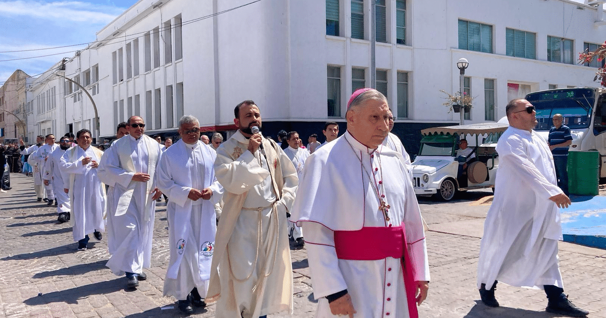 Procesión religiosa con líder en mitra y túnicas blancas en calle soleada