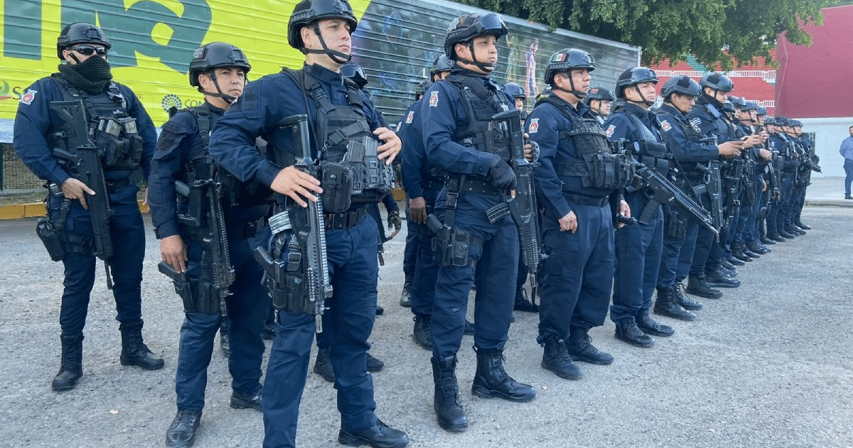 Policías en formación táctica en Culiacán con equipo completo frente a una pared con grafitis.
