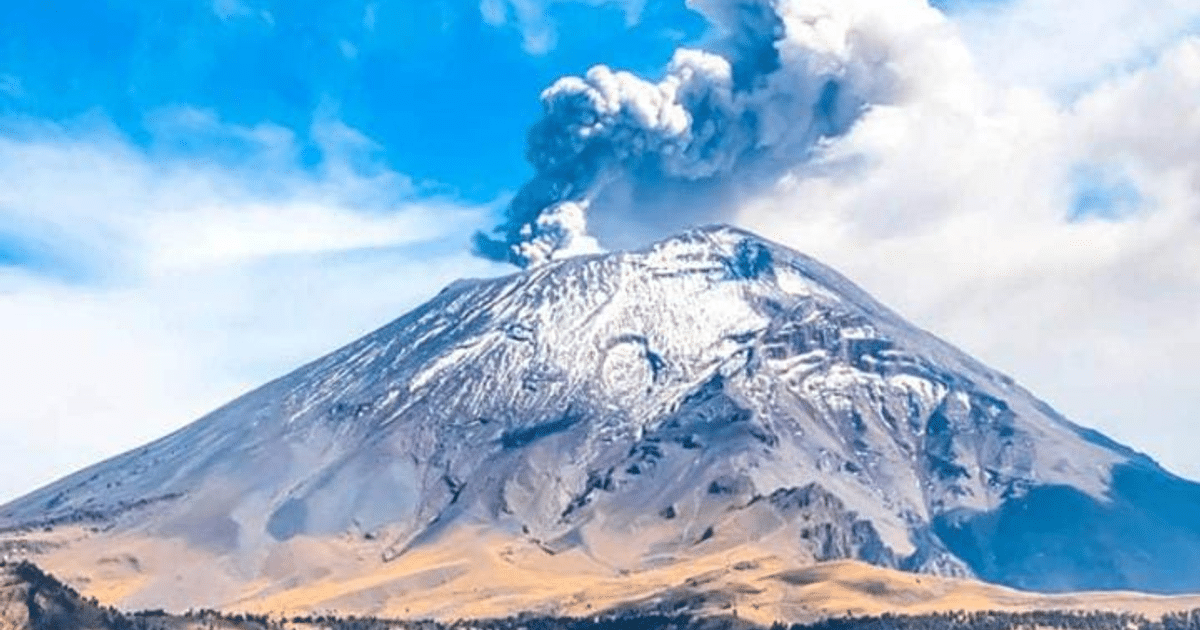 Volcán Popocatépetl emitiendo humo con cumbre nevada y cielo azul