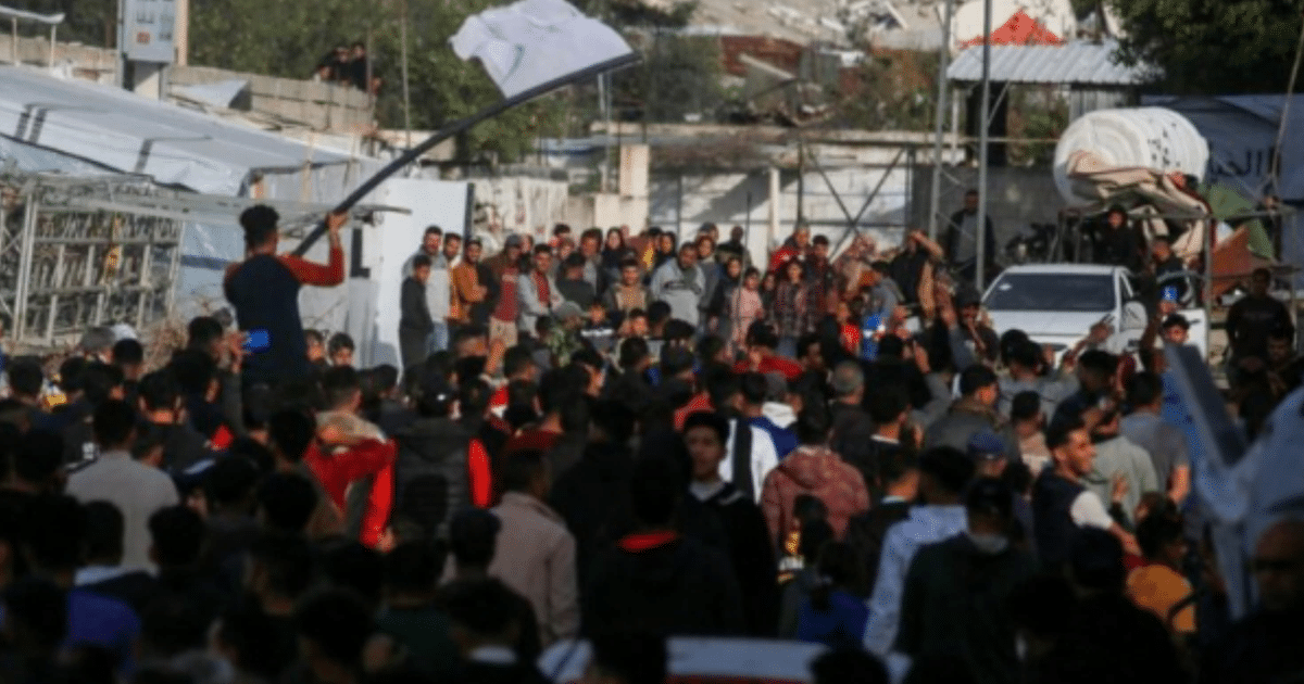 Manifestación en Beit Lahia, Gaza, con personas levantando las manos y una bandera blanca en el centro.